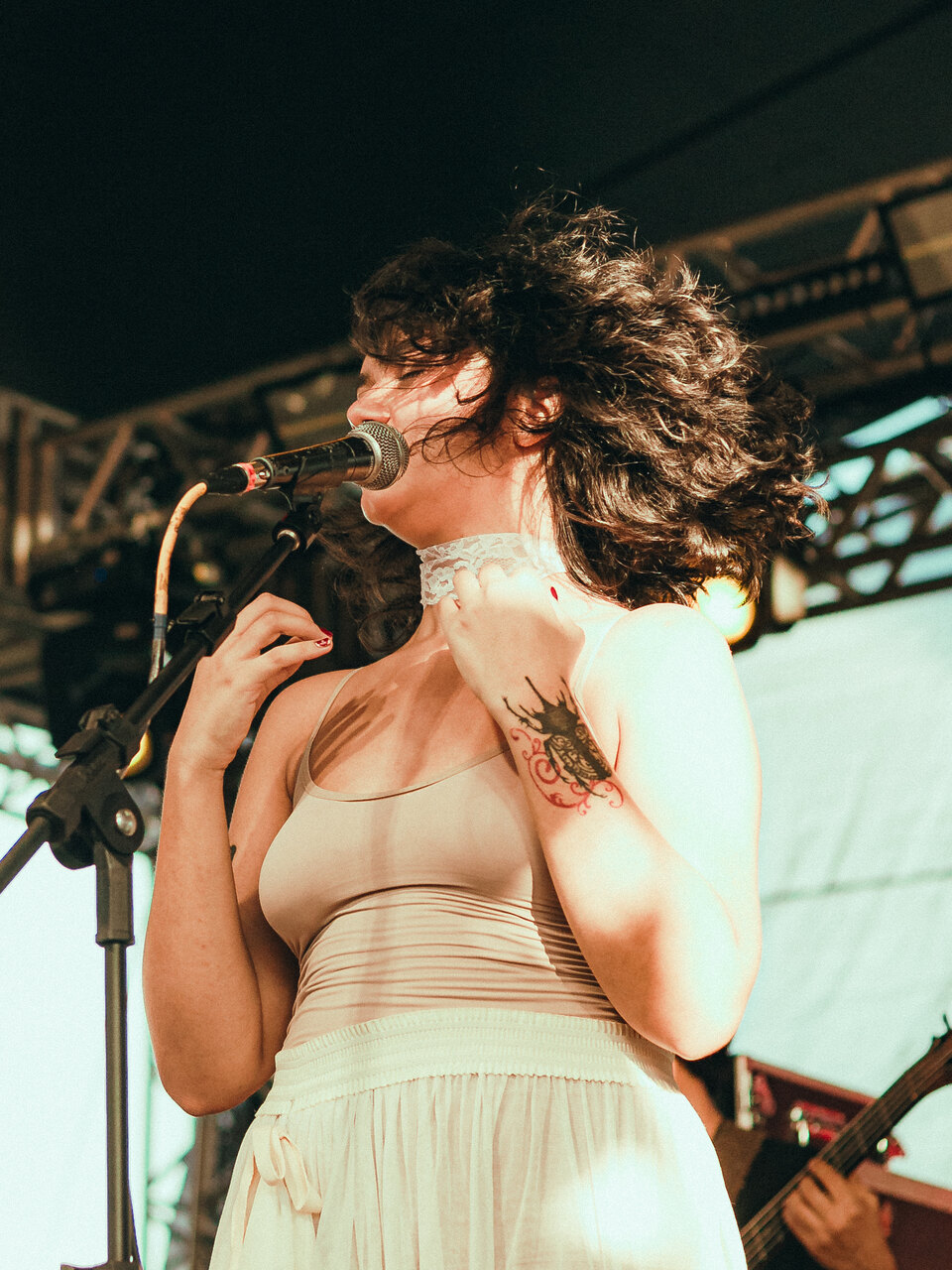 BRUNÊ cantando de olhos fechados, tatuagens no braço, num show à tarde